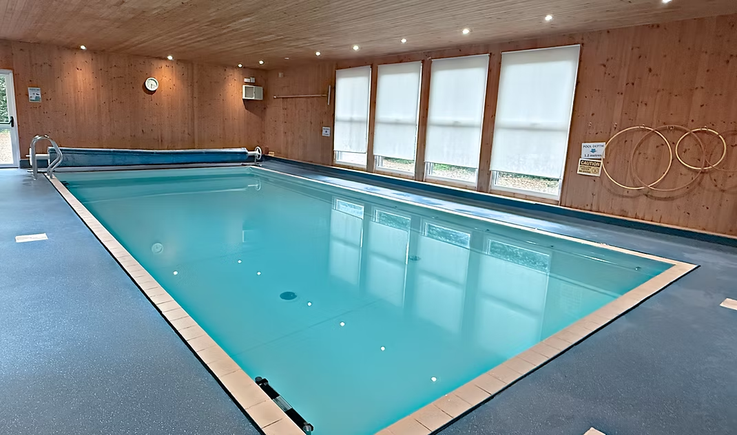 The main pool at The Little Swim Club, a warm indoor pool with cedar-clad walls and large windows